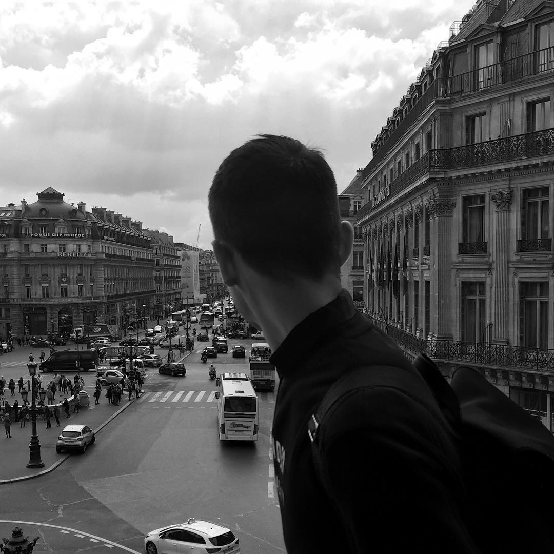 A black-and-white photo of Wilton Gorske looking over his right shoulder in Paris while wearing an Acne backpack and sweatshirt